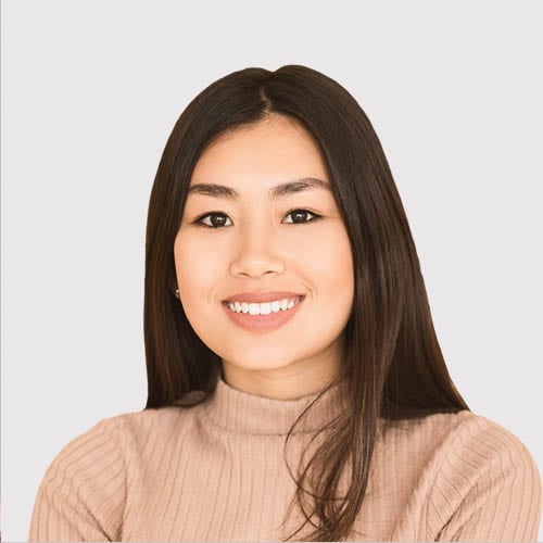 Smiling young woman with long dark hair in a beige sweater.