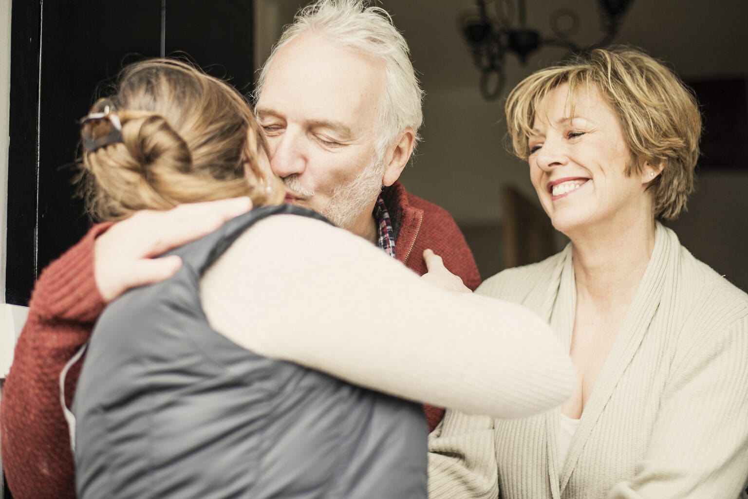 Supportive family moment with elderly man and women embracing young girl.