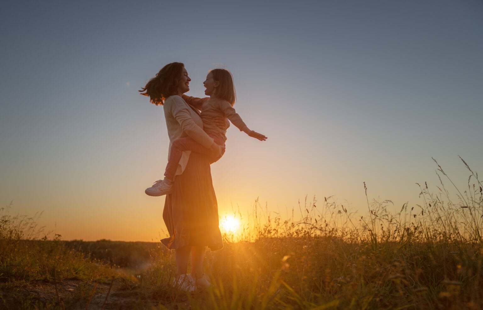 Mother and daughter enjoying sunset outdoors, symbolizing family support and well-being.