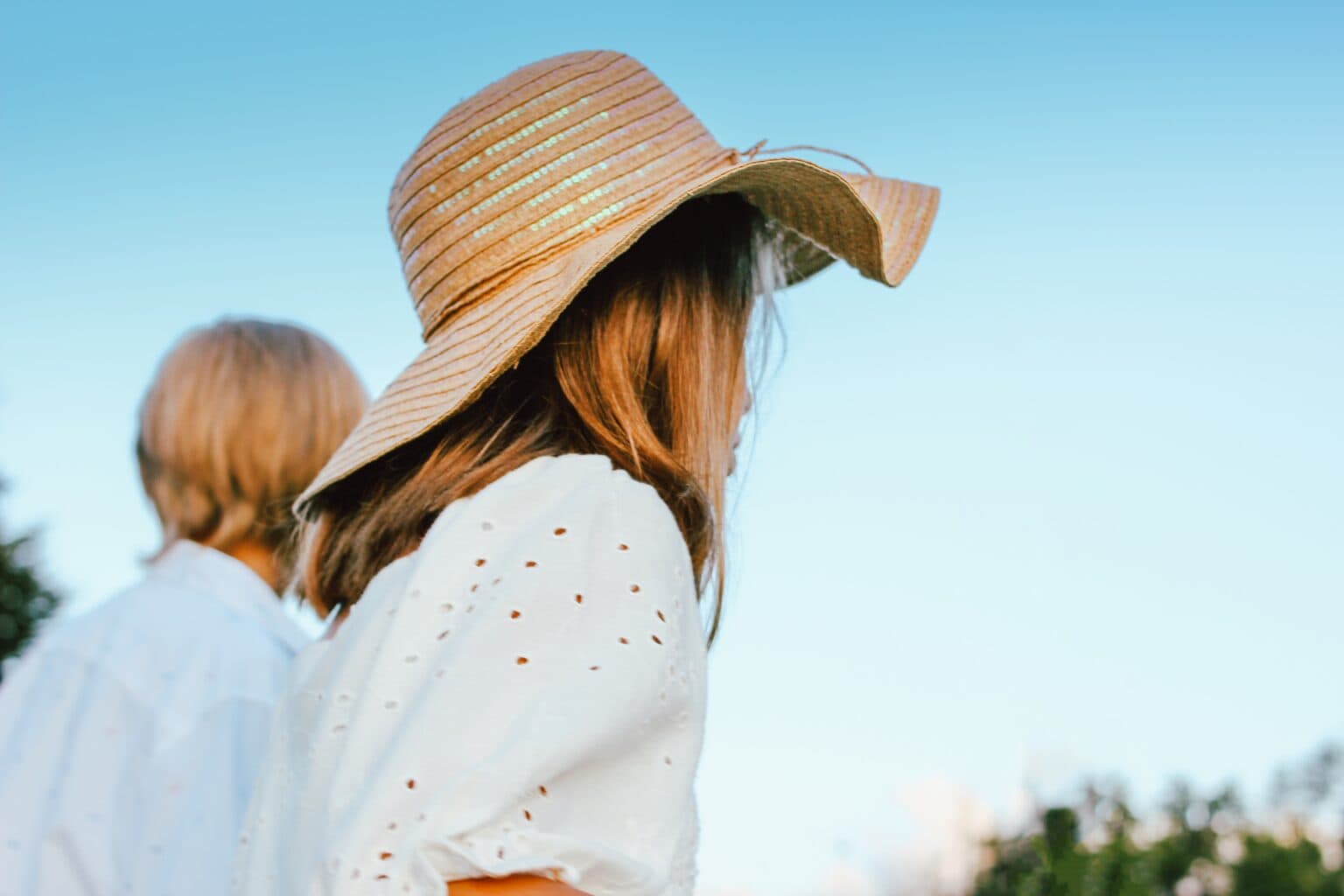 Woman wearing a straw hat enjoying sunny outdoor day.